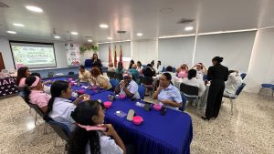 Grupo de colaboradoras y personal del Hospital Universitario del Caribe participando en un taller dinámico de autocuidado y bienestar en un auditorio con proyección del Día Mundial de la Salud Mental.
