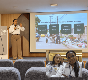 Ponente en el podio de la UNAD realizando una presentación sobre el fenómeno de habituación en un auditorio, mientras representaciones del Hospital Universitario del Caribe asisten a la jornada académica.