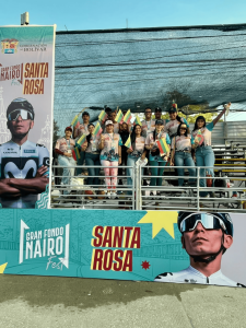 Integrantes de la delegación del Hospital Universitario del Caribe con camisetas institucionales y banderas del departamento de Bolívar en una tarima durante el Gran Fondo Nairo Fest en Santa Rosa de Lima.